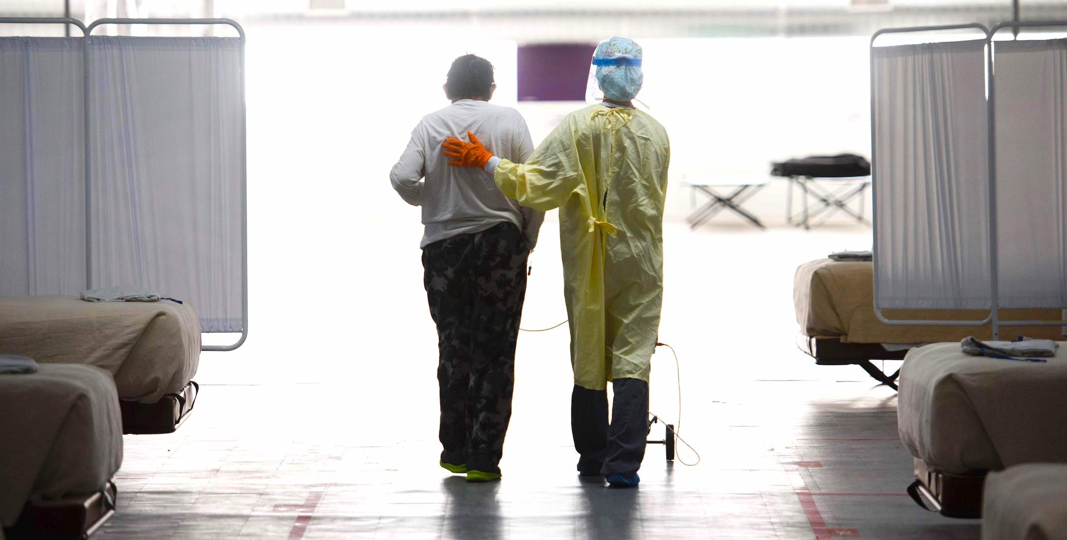 A nurse supports a patient as they walk in the Covid-19 alternative care site, built into a parking garage, at Renown Regional Medical Center, on December 16, 2020 in Reno, Nevada. | Patrick T. Fallon / AFP via Getty Images