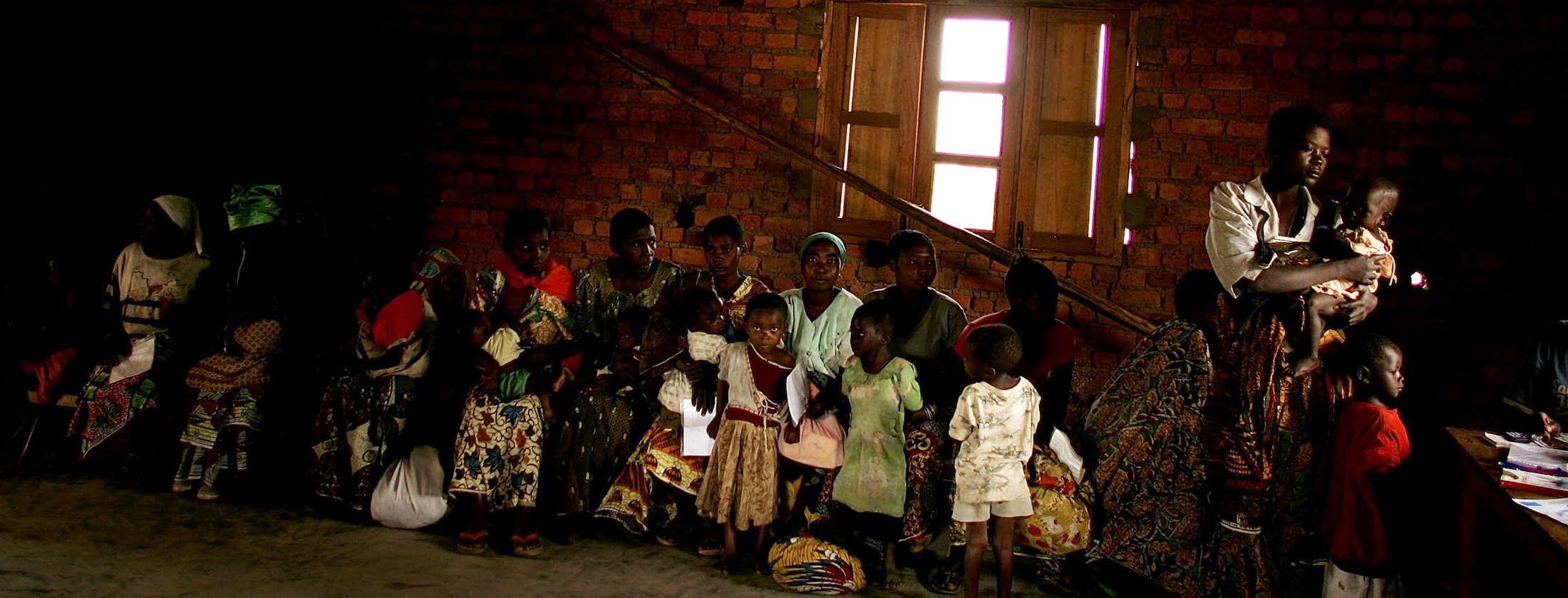 Women and children in a waiting room with brick walls