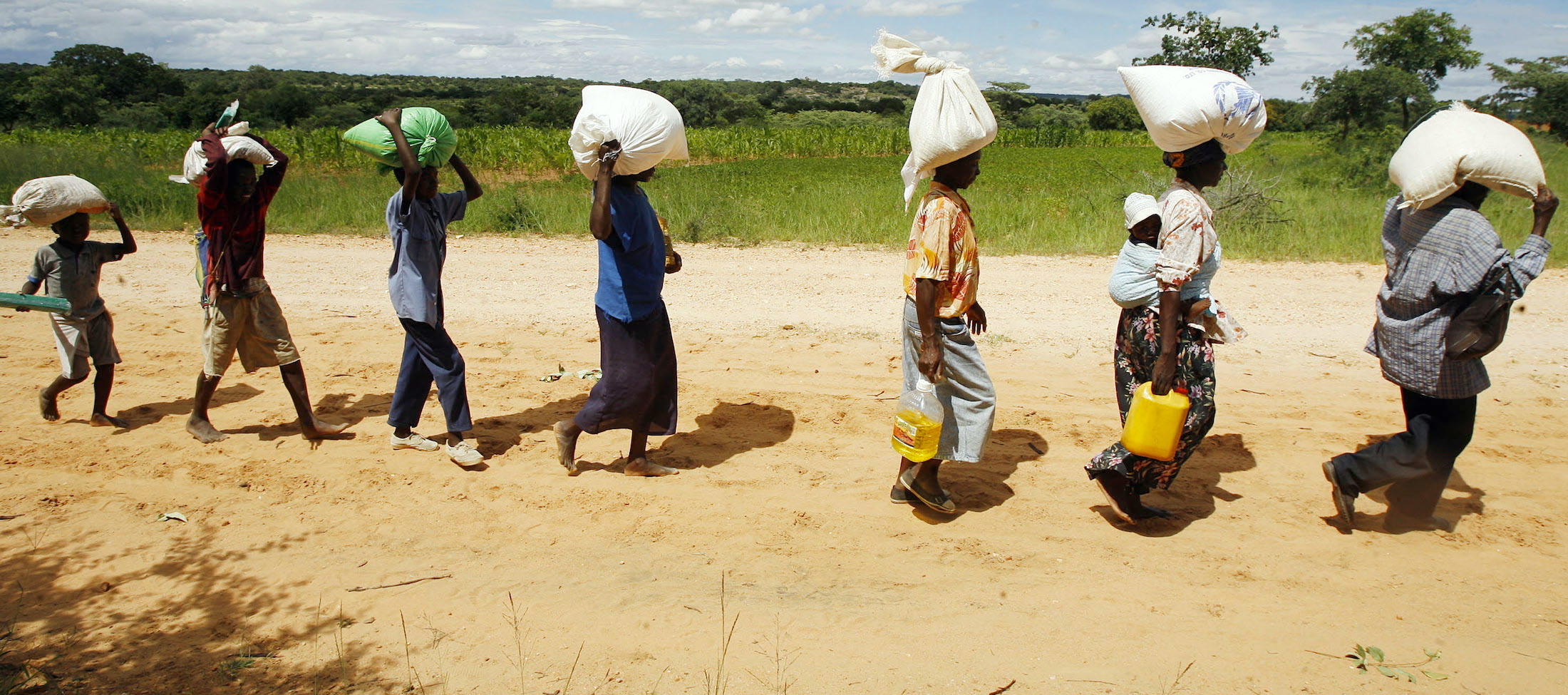 People carrying rice bags on head while walking down road
