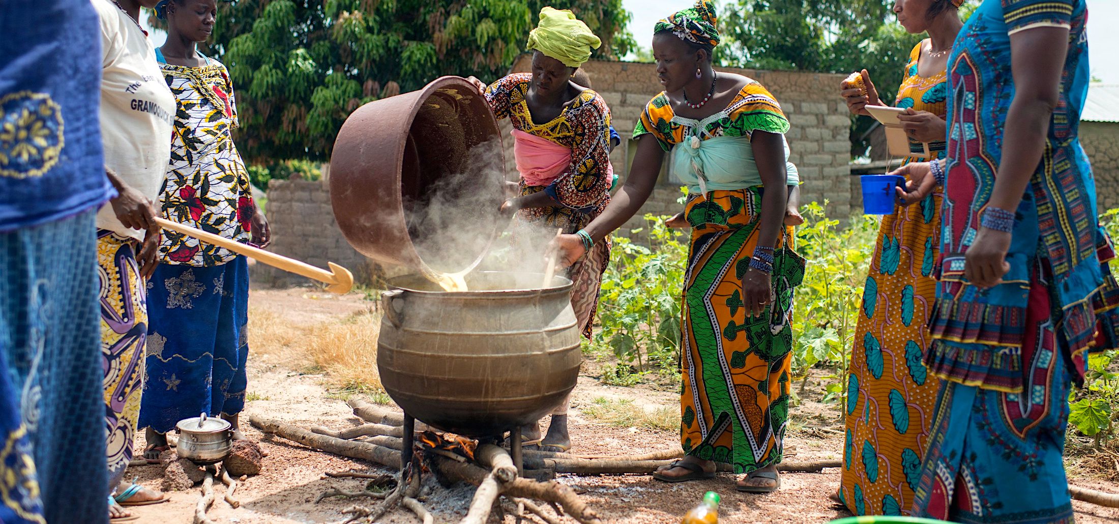 Women working together around a big pot making food for everyone