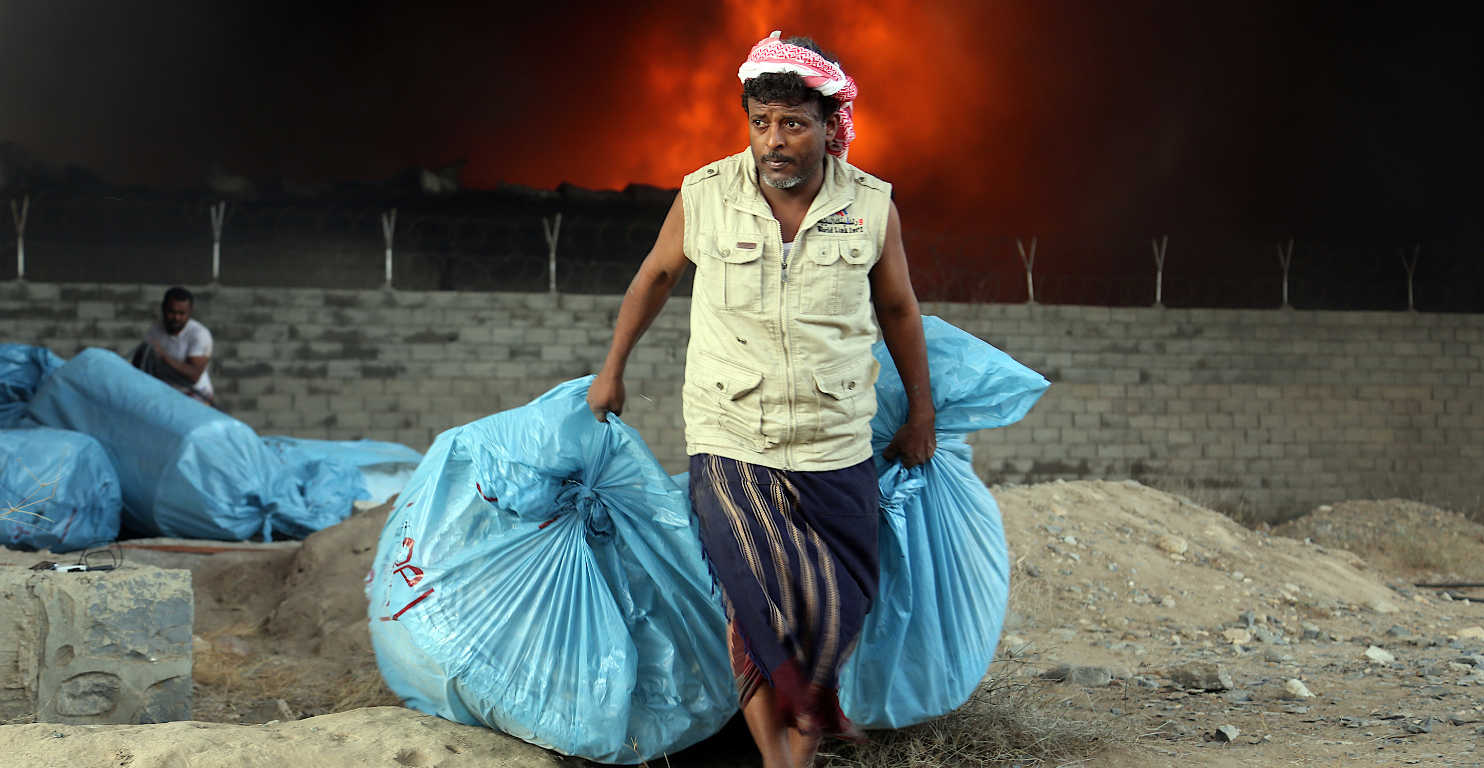 A worker fights to save food bags from the fire engulfing a World Food Program warehouse in the Houthi-held coastal town of Hodeida, Yemen | ABDO HYDER/AFP/Getty Images