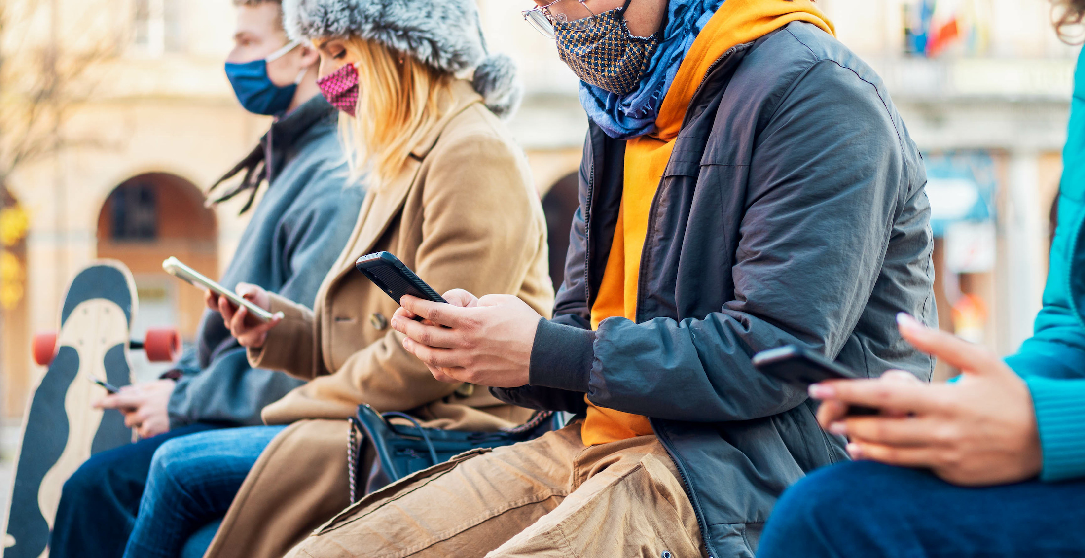 Socially distanced people use their phones to track the rates of Covid-19 in 2020. | Davide Angelini via Adobe Stock