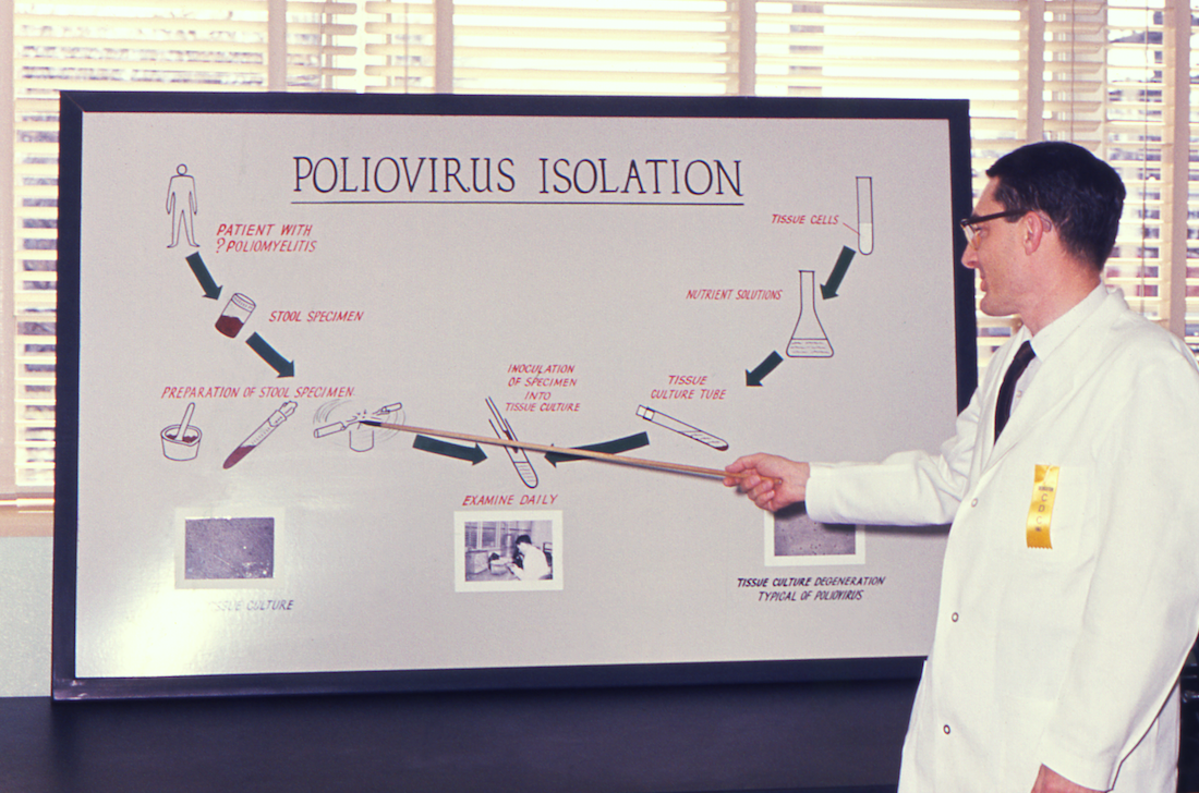 A public health scientist in 1961 explaining the laboratory techniques involved in the isolation of the poliovirus.