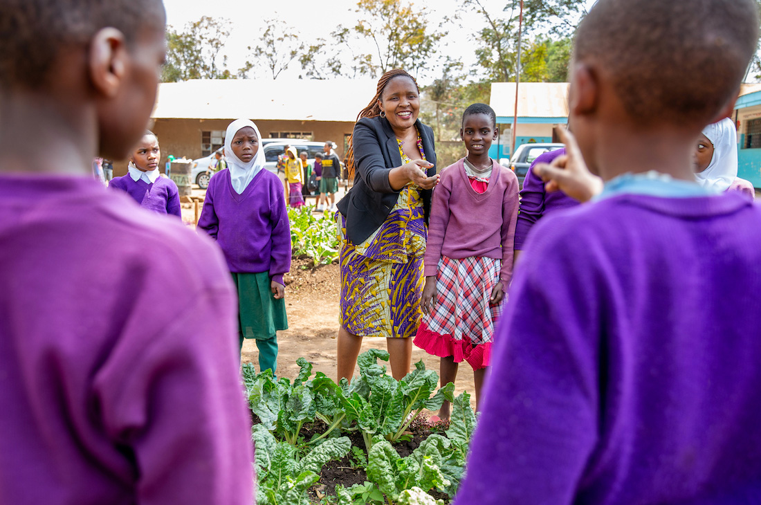 Children gathered around garden with teacher