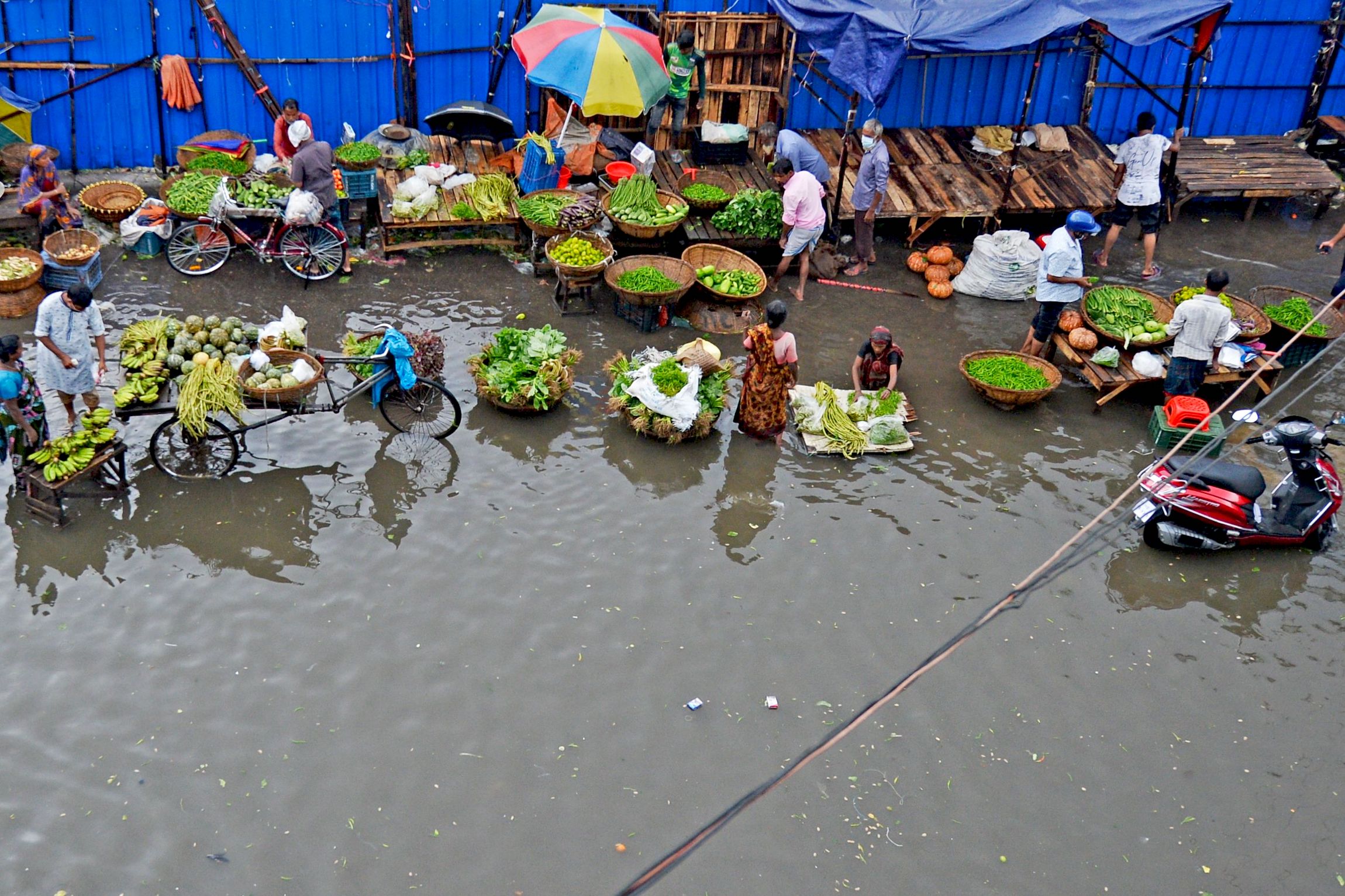 Vegetable vendors wait for customers as they sit in a water-logged street after a heavy downpour in Dhaka on July 21, 2020. | MUNIR UZ ZAMAN/AFP via Getty Images