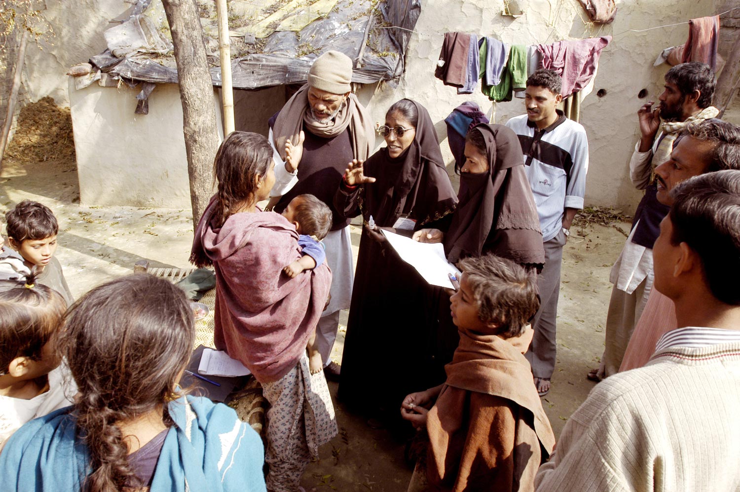 Health workers and villagers try to convince a woman to let her children be vaccinated against polio in Moradabad