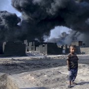 Young child standing in front of smoking buildings