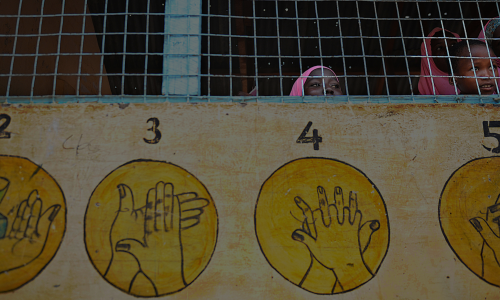 Young Somali girls peer through the window of a classroom of the Undugu primary school at the sprawling Dadaab refugee complex in northeastern Kenya. | TONY KARUMBA/AFP via Getty Images