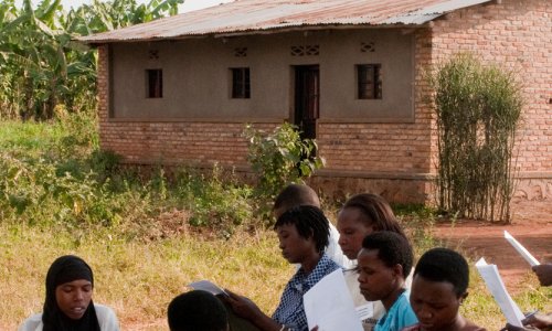 A group of people sitting on grass attend a community health worker training in Rwanda.