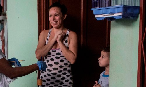 A health worker talk to a mother and her young child at their door to persuade them to get tested for COVID-19.