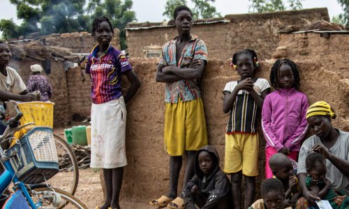 A community health worker speaks with a mother and a group of children about malaria prevention in Burkina Faso.