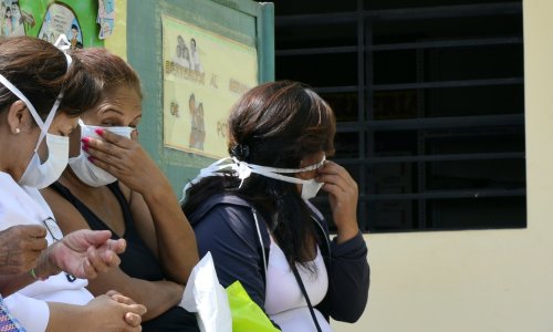 Women wear face masks as they wait to be assisted at a public clinic in Lima on April 14, 2015. | CRIS BOURONCLE/AFP via Getty Images