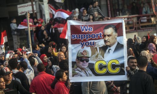 Egyptian men hold a poster with a portrait of late president Gamal Abdel Nasser and Egypt's Defence Minister General Abdel Fattah al-Sisi outside a polling station during the vote on a new constitution on January 14, 2014 in Giza, Cairo. Egyptians queued to vote on a new constitution today amid high security, in a referendum likely to launch a presidential bid by the army chief who overthrew Islamist president Mohamed Morsi. AFP PHOTO/MAHMOUD KHALED 