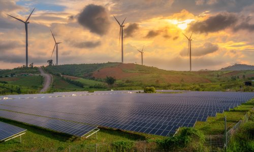 solar panels and wind turbines generating electricity in power station green energy renewable with sunset background