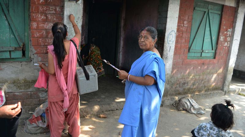 Indian health workers mark the wall of a house to show children there have received the polio vaccine