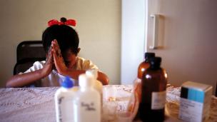 A nine-year-old girl in Johannesburg prays before taking her antiretroviral HIV-AIDS drugs.