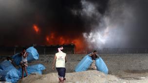 Yemeni workers evacuate food bags as fire engulfs a rebel-held United Nations' World Food Program warehouse in 2018 | ABDO HYDER/AFP/Getty Images 