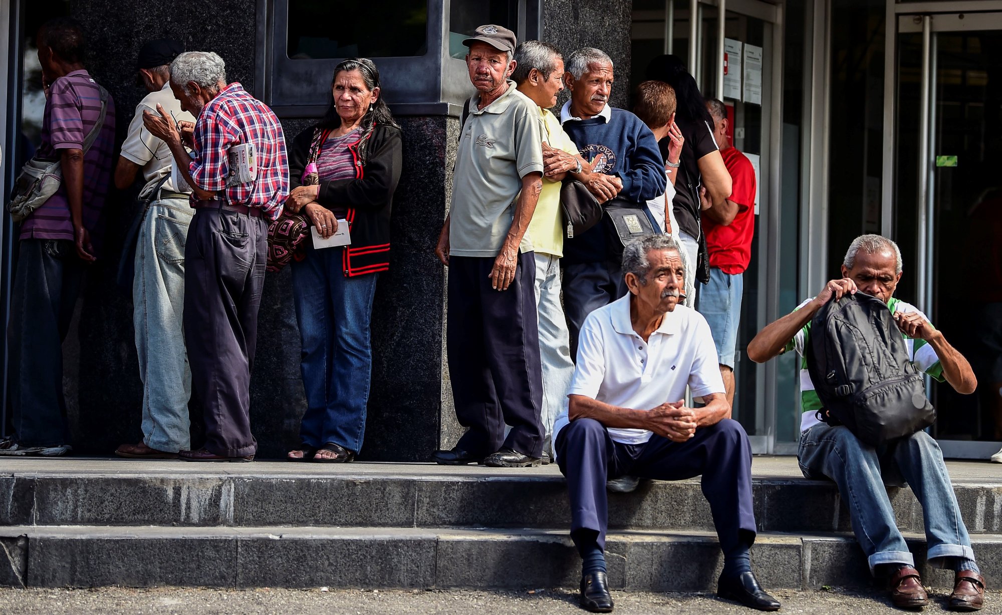 Elderly people wait for their pension monthly payment outside a bank in Caracas, on February 22, 2019. 