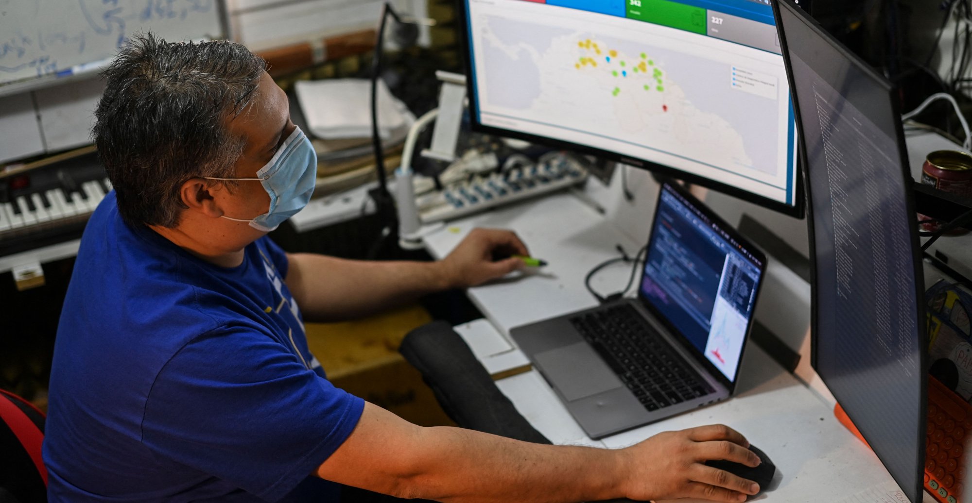 Venezuelan Jose Miguel Avendano, works on his computers as he shows an application designed by him that allows locating health centers and hospitals as well as the most feasible route to reach them in the case of emergencies due to the COVID-19 in the La Candelaria neighborhood, Caracas on May 11, 2021.
