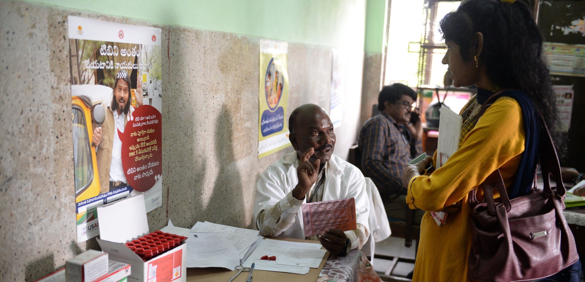 A medical supervisor (C) holds a packet of medicine to treat tuberculosis (TB) as he talks with a patient in the government-run Osmania General Hospital in Hyderabad on October 30, 2019. | NOAH SEELAM/AFP via Getty Images
