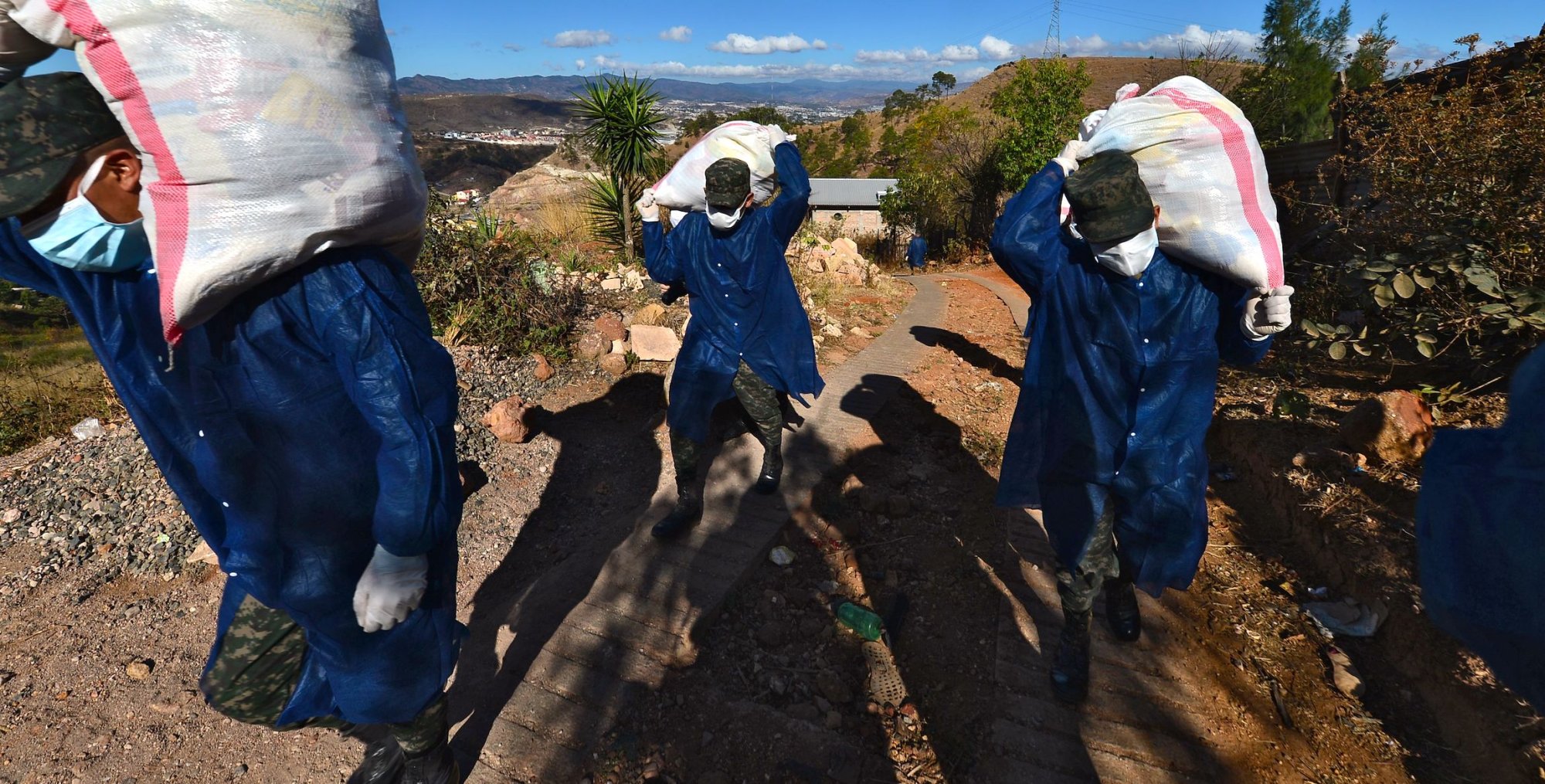 Soldiers wearing face masks distribute food at the deprived Los Pinos community in Tegucigalpa. | ORLANDO SIERRA/AFP via Getty Images