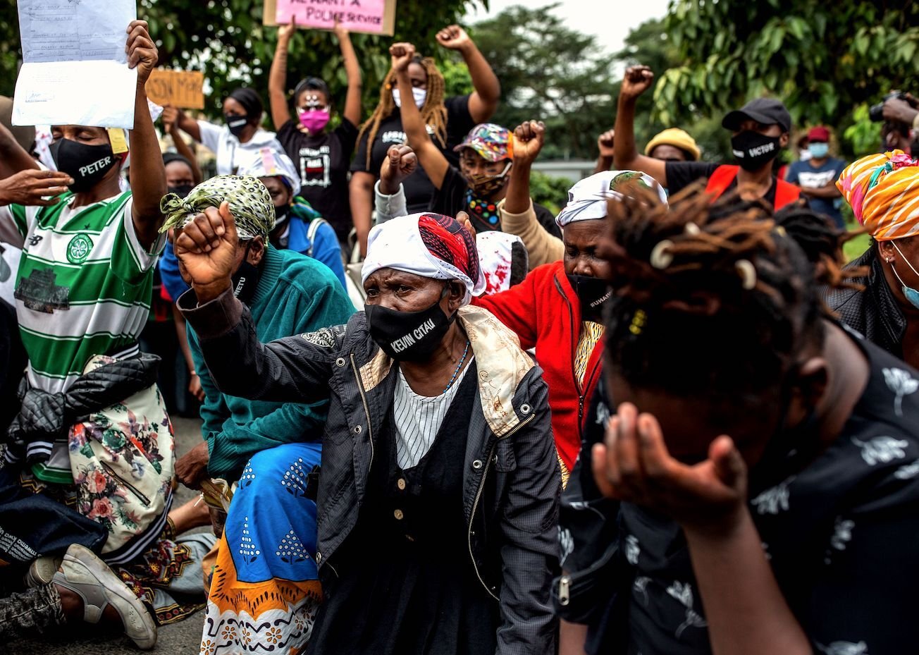 Kevin Gitau's mother (C) wears a mask with her son's name, who was killed by Kenyan Police during a nigh curfew, as she raises her fist in front of the Kenyan Parliament during their protest against police brutality in Nairobi on June 9, 2020. 