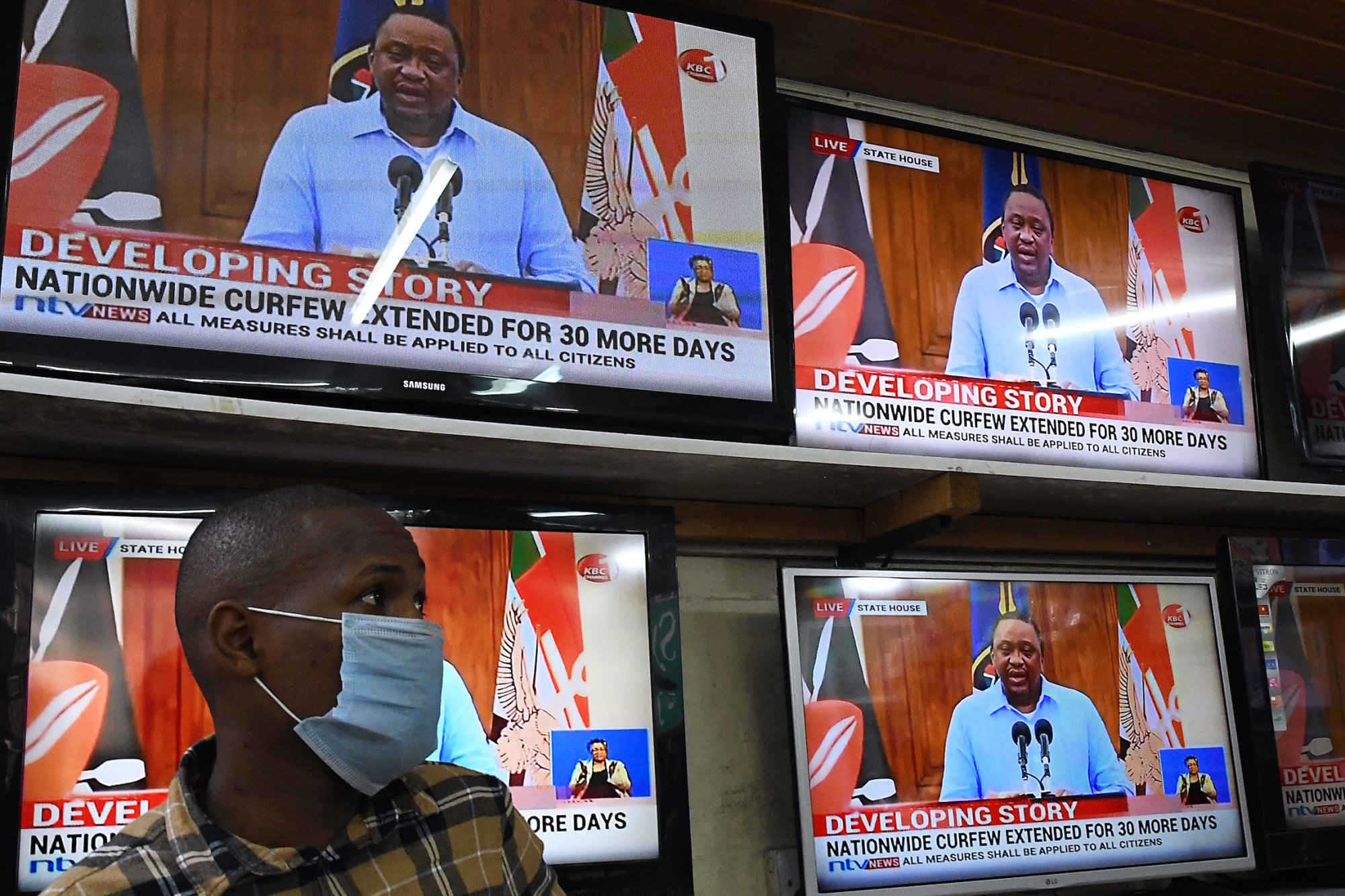 An electronics shop assistant watches on television Kenya's President Uhuru Kenyatta giving a state of the nation address on the coronavirus (COVID-19) pandemic. 